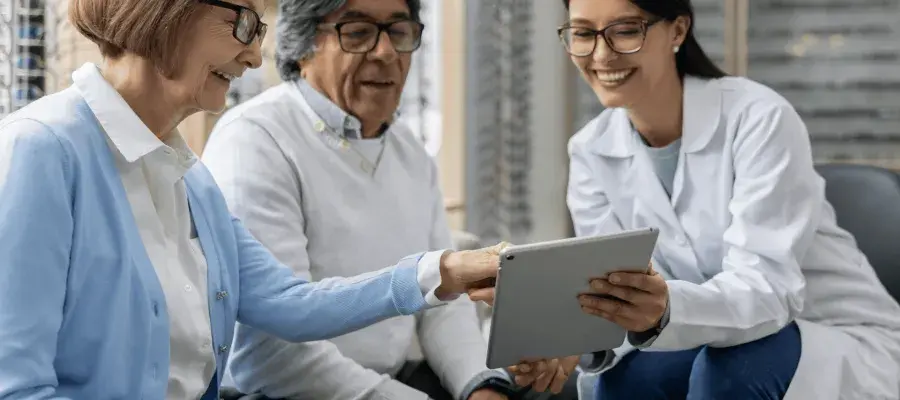 Three people sitting on chairs looking at a tablet