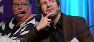 Candid photo of Prof Terry Quinn in a brown jacket smiling off camera