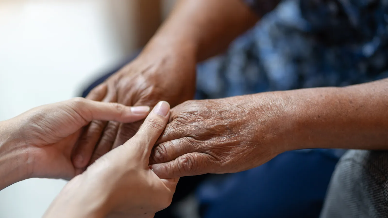close up of two people holding hands against a blurred background