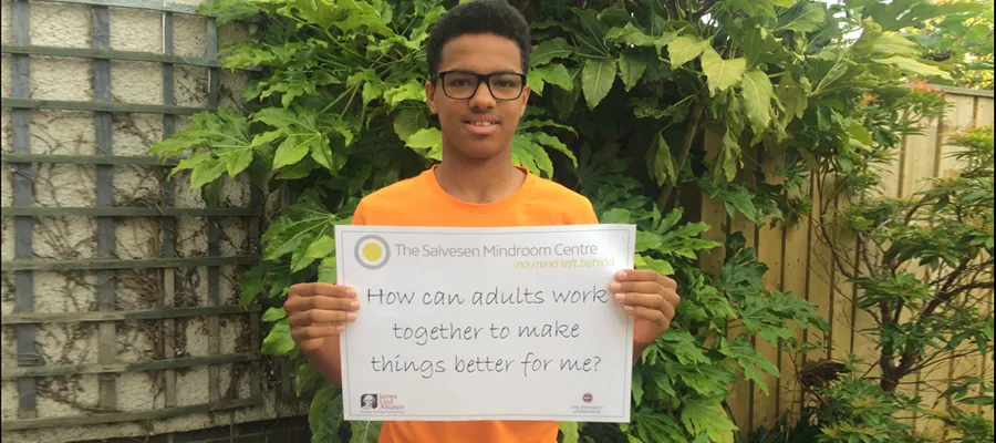 a young man holding up a sign describing what learning difficulties research he would like to be done